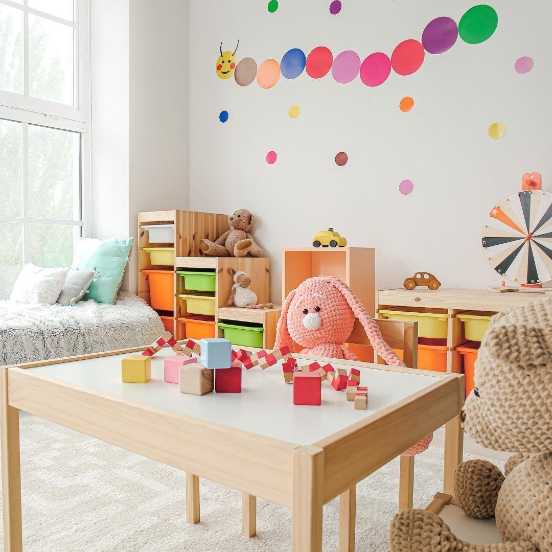 A room with single bed and dining table decorated with soft toys and colorful crafts items in a beautiful way.