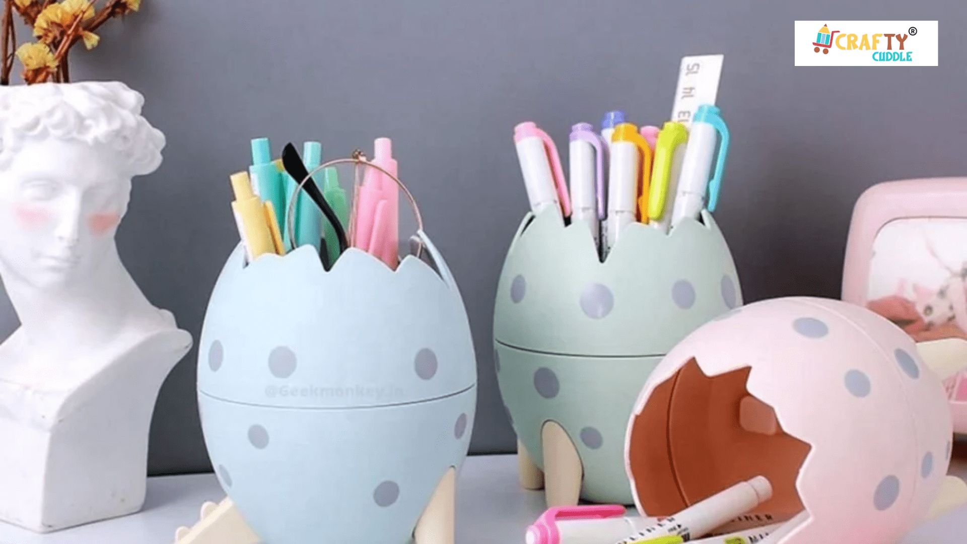 Image of Dino Egg Pen Stand with pens and crayons in it and placed on the table.