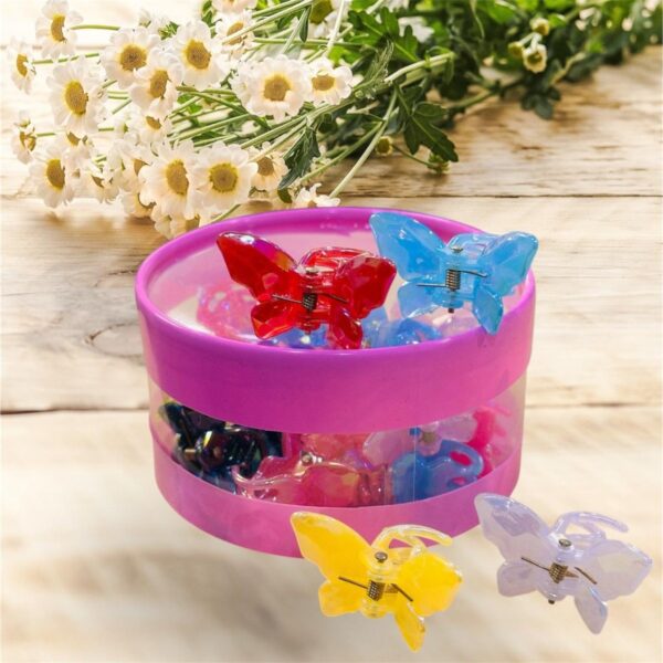 Pink container with colorful butterfly hair clips on a wooden surface with flowers in the background