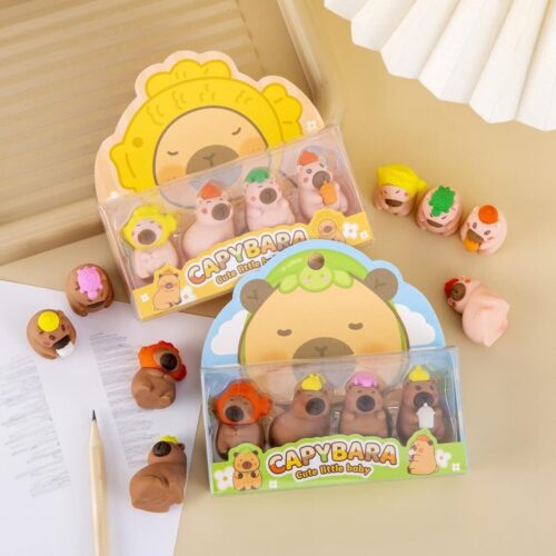 Capybara-shaped erasers in packaging on a light surface with a pencil and notebook.