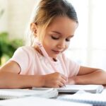 Young girl writing in a notebook with a soft focus background