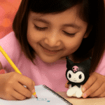 Kuromi 2 - in - 1 Sharpener and EraserStationery > Erasers & SharpenersCRAFTY CUDDLEChild drawing with a pencil, holding a cartoon character figurine, on a blurred warm - toned background2in1SharpenerEraserAnimeStationery