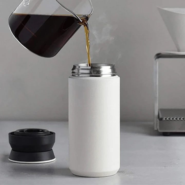 Image of pouring black coffee in the white colored stainless steel bottle.
