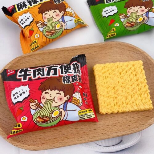 Three instant noodles Erasers packages with a yellow cracker on a wooden tray