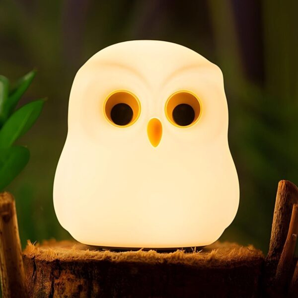 Owl-shaped night light on a wooden stump with a blurred natural background
