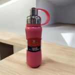 Pink water bottle with a handle on a wooden surface