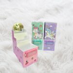 Unicorn Magic pop-up pen stands displayed—one pink box open showing mirror and compartments, and two others closed in lavender and Light green colors.