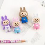 Four colorful cartoon character erasers on a white background with a pen.