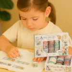 Washi Tape – 20 pcs Memory Post Office SetCRAFTY CUDDLEYoung girl looking at a collection of colorful rolls of paper with a decorative box.