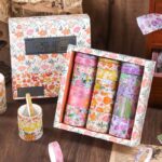 Set of floral washi tape in a decorative box on a wooden surface.