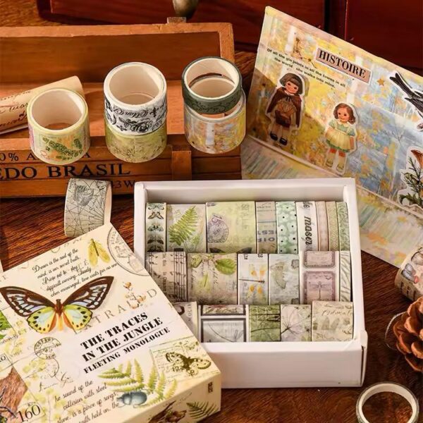 Collection of washi tape rolls on a wooden surface with a book and magazine.