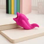 Pink dolphin-shaped object on a notebook with colorful books in the background