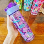 Colorful water bottle with graphics and text held by a hand on a wooden surface