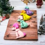 Dog ErasersErasersCRAFTY CUDDLEColorful clay poodle figurines erasers on a wooden board with Christmas decorations in the background.1animalerasersbacktoschoolsupplies