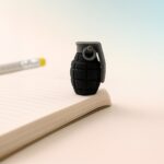Black grenade-shaped eraser on a notebook with a pencil