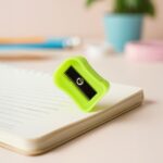Green pencil sharpener on a notebook with a blurred background