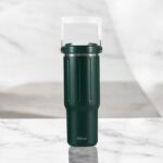 Green travel mug with a white handle on a marble surface