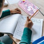 A boy studying at a desk with a pencil pouch placed inside the table compartment, organized with pens and stationery items