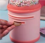 Close-up of Hand Inserting Money into Peach Unicorn Piggy Bank with Locker – Fun Way for Kids to Save