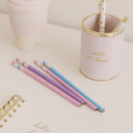 Pastel-colored pencils with a pink holder labeled 'write it down' on a light surface.