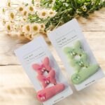 Two hair clips, one pink and one green, on white cards with floral background