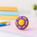 Purple and yellow fidget eraser on a desk with stationery items