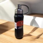 Black insulated bottle with a label on a wooden surface