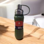 Green water bottle with a label on a wooden surface