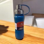 Blue vacuum insulated bottle on a wooden table with a blurred background
