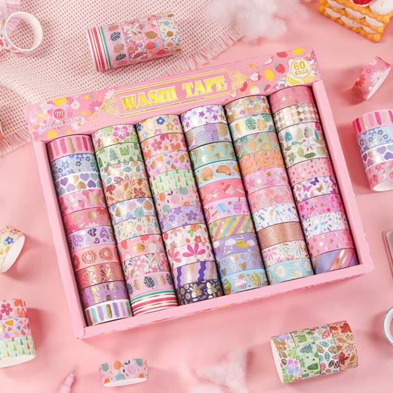 Set of colorful washi tape rolls in a decorative box on a pink background