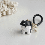 Dog-shaped keychain with black and white design on a light gray background