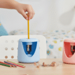 Electric Pencil SharpenerStationery > Erasers & SharpenersCRAFTY CUDDLEChild's hand using a blue pencil sharpener with a yellow pencil, surrounded by colored pencils on a wooden surface.BlueElectricSharpener StationeryEssentials SchoolSupplies StudyDesk OfficeSupplies BackToSchool SmartStationery DeskSetup StudentEssentials StationeryAddict