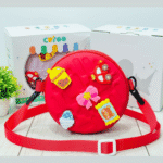 Kids Round Sling BagKids BagsCRAFTY CUDDLERed children's bag with colorful decorations on a light wooden surface.RedKidsSlingBag CuteKidsFashion GirlsCrossbody MiniSlingBag KidsAccessories CartoonBag TrendyForKids BirthdayGiftIdeas ReturnGiftIdeas KidsStyle