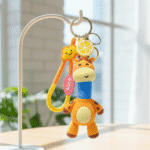Colorful giraffe-shaped keychain with a lemon and a smiley face on a stand.