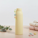 Leak Proof Mini Glass BottleCartoon Kids Water BottleCRAFTY CUDDLEBeige ribbed water bottle with decorative elements on a light backgroundYellow330mlBottle GlassWaterBottle MiniWaterBottle LeakProofBottle SiliconeSleeveBottle TravelWaterBottle OfficeWaterBottle ReusableBottle PastelBottle EcoFriendlyBottle
