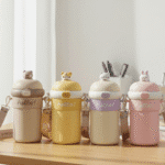 Four colorful water bottles with animal-shaped lids on a wooden surface.