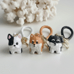 Four dog-shaped keychains on a white surface with a coral-like background