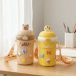 Bouncing Straw Glass Cup with StrapCartoon Kids Water BottleCRAFTY CUDDLETwo colorful water bottles with cartoon designs on a wooden surface.Cream PurpleBouncingStrawCup KidsGlassBottle 510mlBottle StrawWaterBottle LeakProofBottle KidsWaterBottle SchoolWaterBottle CuteCharmsBottle ReusableGlassBottle CartoonWaterBottle