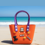 Cute Cartoon Charm Tote Bag for KidsKids BagsCRAFTY CUDDLEOrange beach bag with purple handles on a sandy beach with ocean in the backgroundOrangeKidsToteBag BeachBag SummerAccessories CuteKidsStyle GirlsHandbag WaterproofBag CartoonBag TrendyKids VacationReady GiftForGirls