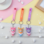 Three colorful keychains with cartoon characters on a pastel background