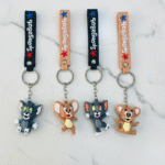 Four keychains featuring cartoon characters on a marble surface