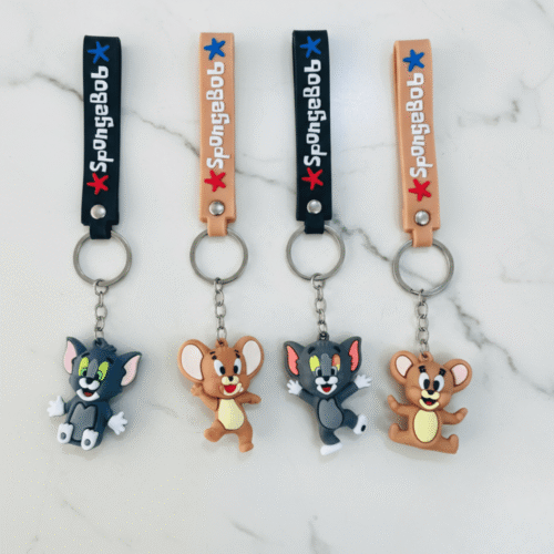 Four keychains featuring cartoon characters on a marble surface