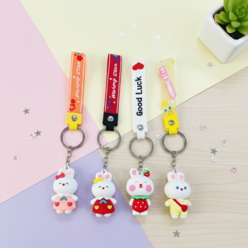 Four colorful keychains with cartoon characters on a pink and blue gradient background
