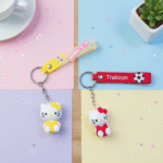 Hello Kitty Silicone KeychainKeychainsCRAFTY CUDDLETwo Hello Kitty keychains on a colorful background with a cup and plant.1CuteKeychain CartoonCat KawaiiAccessories KittyKeychain GirlsBagCharm BackpackCharm SiliconeKeychain ReturnGifts TrendyKeychains GiftForGirls