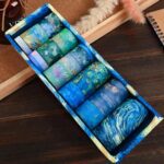 Set of blue washi tape rolls in a decorative box on a wooden surface.