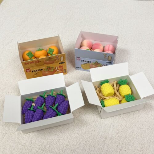 Four boxes of fruits and vegetables erasers on a light gray surface