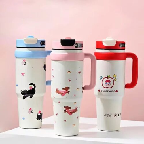 Three colorful travel mugs with cartoon designs on a pink background