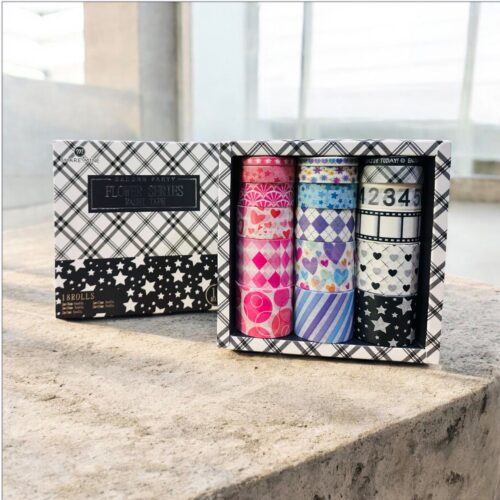 Set of washi tape rolls in a decorative box on a stone surface.