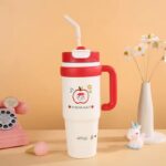 1000ml Stainless Steel Insulated TumblerTumblersCRAFTY CUDDLEWhite tumbler with red lid and handle, featuring cartoon characters, on a beige background.RedInsulatedTumbler StainlessSteelMug TravelTumbler 1000mlBottle VacuumFlask HotAndColdBottle BPAFree CoffeeOnTheGo CarCupHolderFriendly ReusableDrinkware