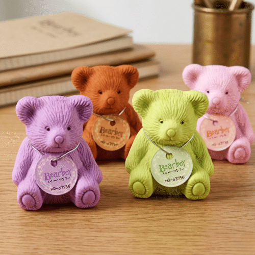 Four colorful teddy bears on a wooden surface with books in the background